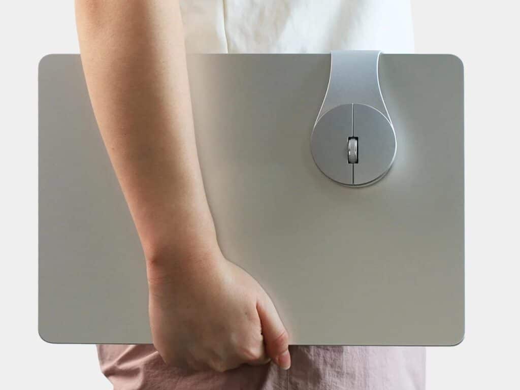 A person carrying a laptop under their arm with a Bondclip mouse securely attached to the device.