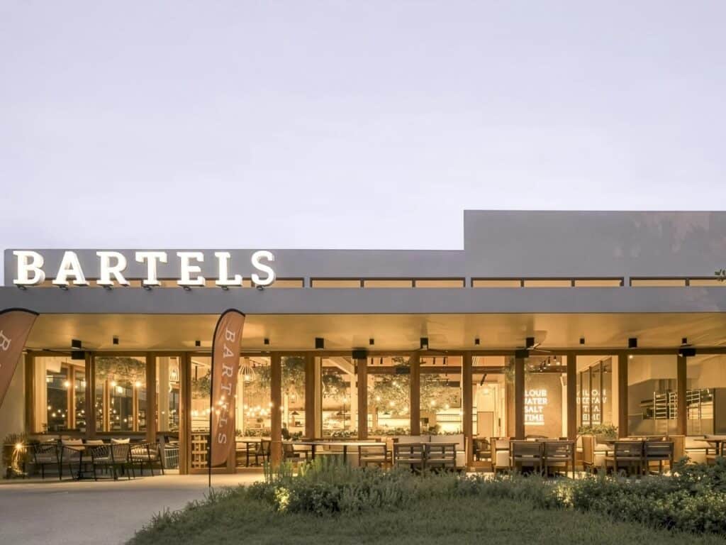 Exterior of Bartels store at My Front Yard with warm lighting and outdoor seating area.