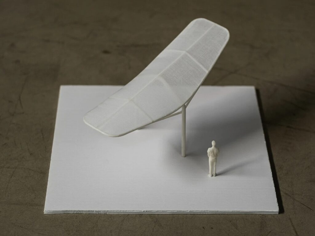 A small-scale white 3D model of the Seoul Wing canopy being held by a hand to show scale against a human figure.