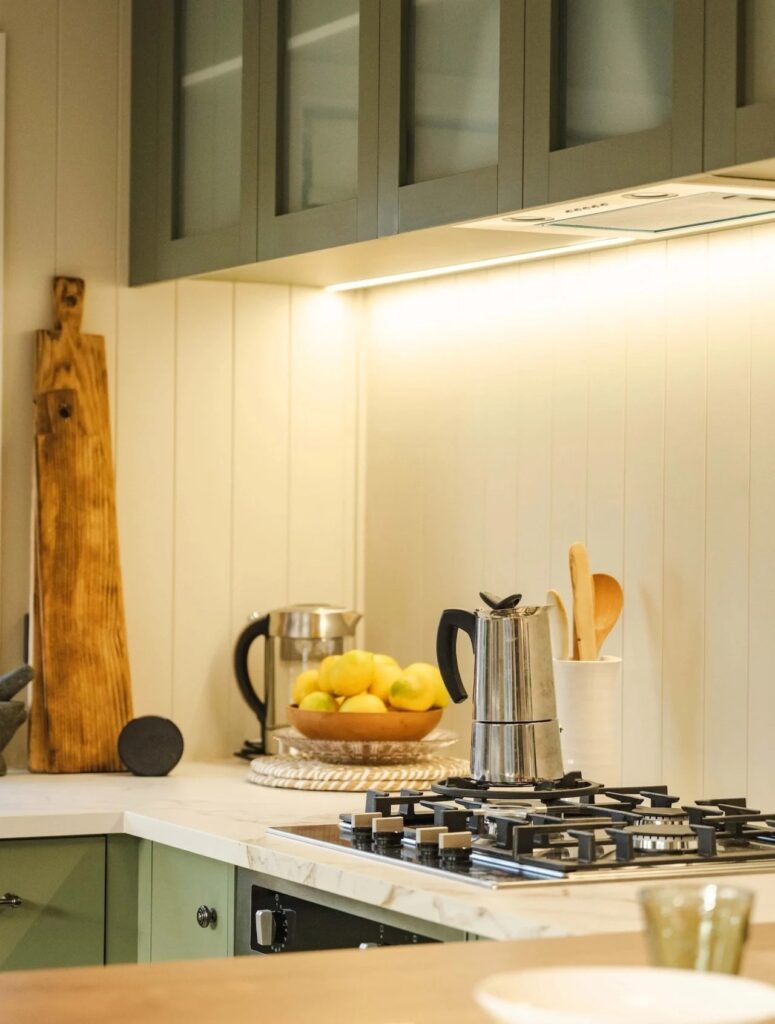 Close-up of a modern gas stove and marble-effect countertop with professional culinary tools in a tiny house.