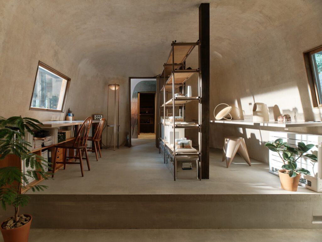 Spacious design studio within Haniyasu House featuring soil-based floors, cantilevered desks, and architectural models.