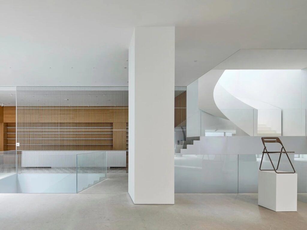 Minimalist interior featuring white walls, decorative screening, and a modern chair on a pedestal.