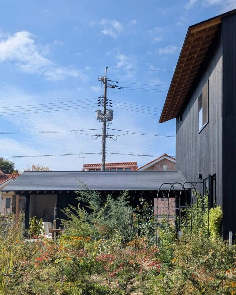 Perspective of the sheltered courtyard at Onomichi House with the studio building and garden arch in the foreground.