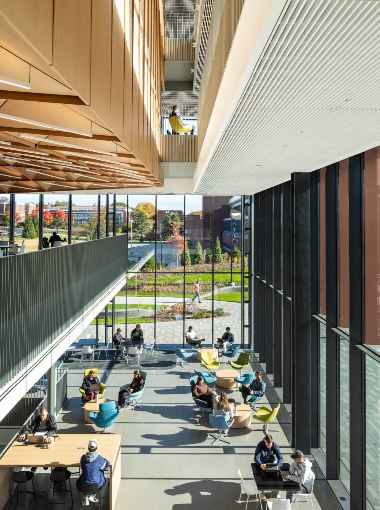 High-angle view of a bright, sun-filled atrium at ECoRE with students working in colorful seating areas.