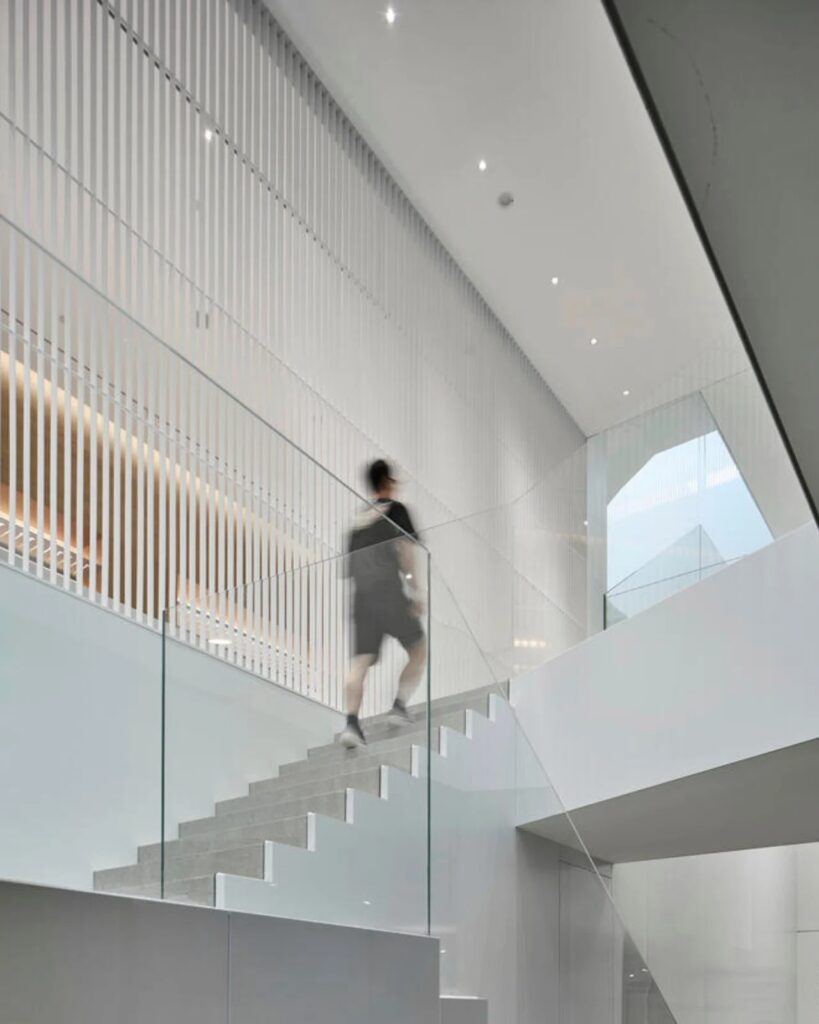 A visitor ascending the staircase behind a translucent screen in the Hangzhou Empathy Museum.