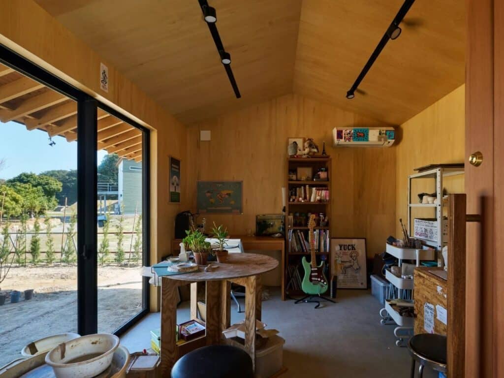 Wide interior shot of the Onomichi House studio showing personal belongings, books, and a glass door leading to the garden.