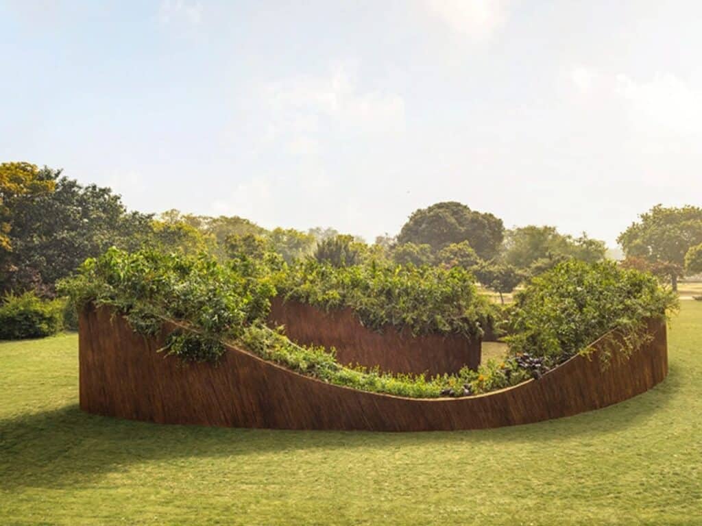 Rear view of the Aranyani Pavilion showing the curved flow of the woven walls and the integrated native plant species.