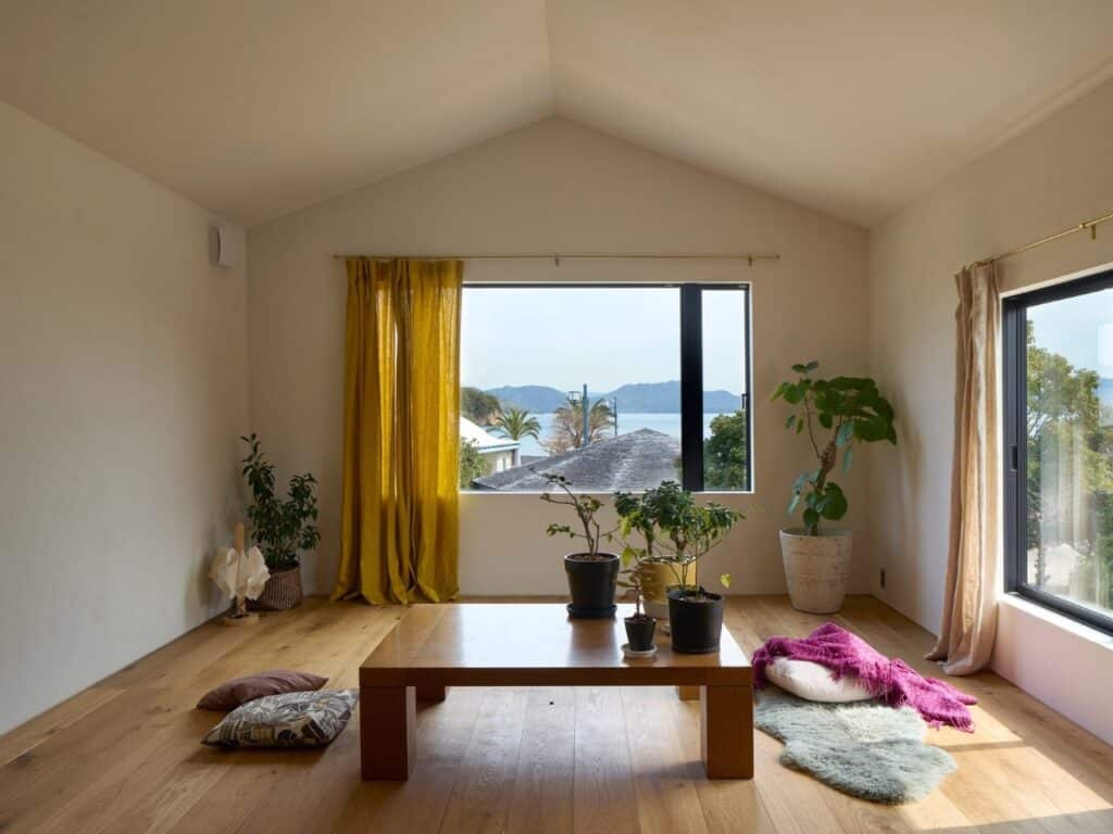 Bright interior of the upper-floor living room in Onomichi House with a wide window overlooking the sea and mountains.