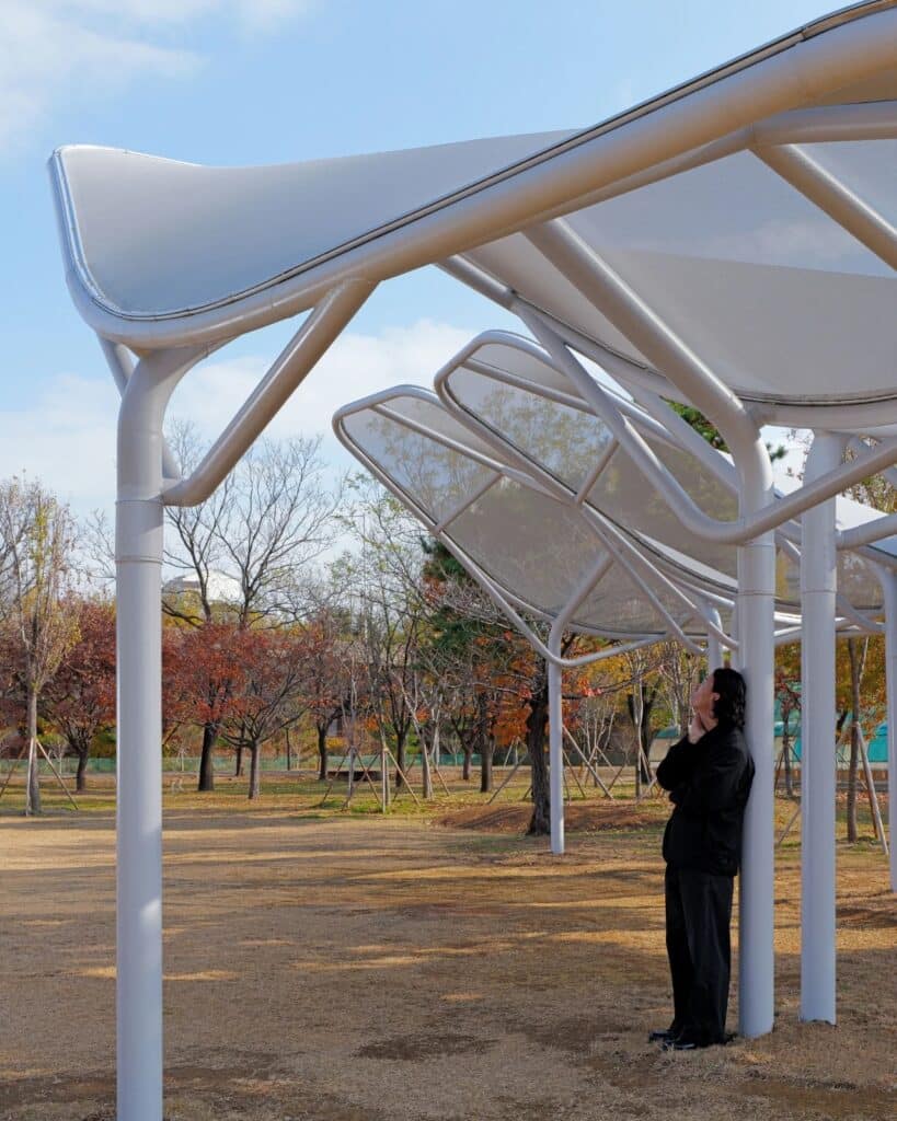 A person standing underneath or next to the Seoul Wing canopies, illustrating the human scale of the urban infrastructure.