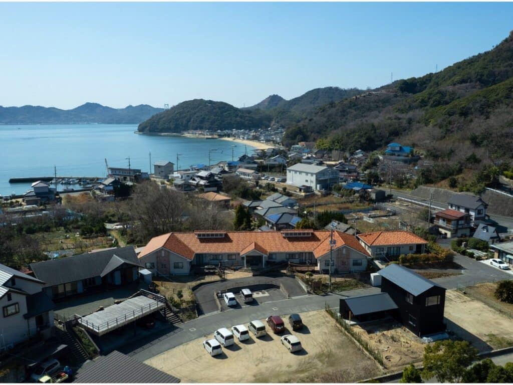 Aerial drone view of Onomichi House and its surrounding neighborhood, showing its proximity to the coastline of the Seto Inland Sea.