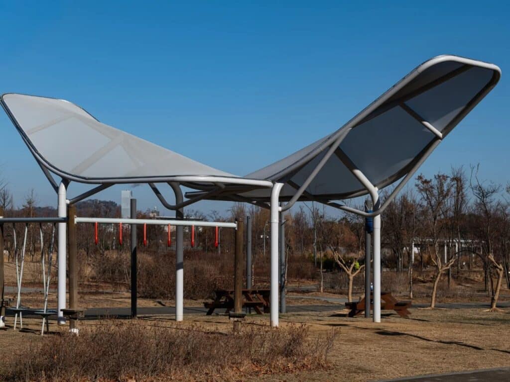 A person standing underneath or next to the Seoul Wing canopies, illustrating the human scale of the urban infrastructure.