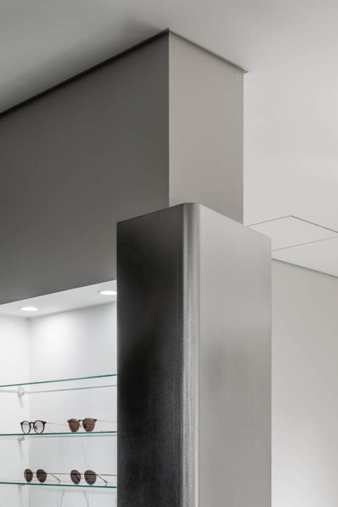 Architectural detail of a metal-clad column meeting the ceiling in Ashiya Optical Store.