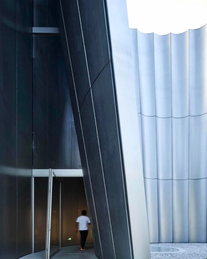 Entrance of the Hangzhou Empathy Museum showing the sharp angles and the transition from the curved facade to the interior.