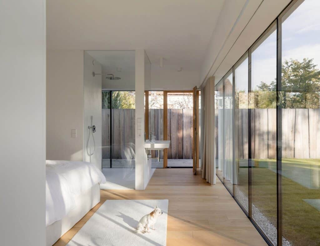 Minimalist modern bedroom with glass walls and direct views of the private garden in Sestajovice House.