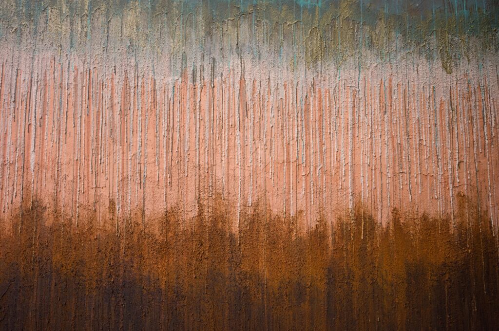 Macro view of a wall texture at Haniyasu House showing vertical drips of light plaster over deep brown and rust-colored soil layers.