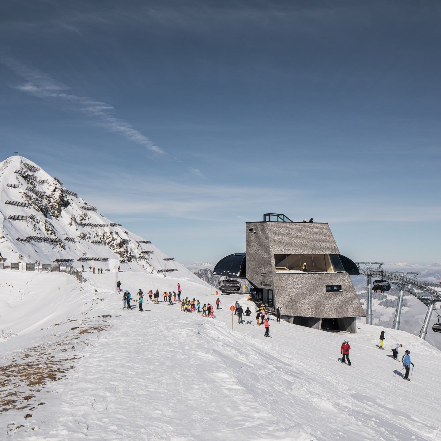 Wide view of the new Alpine Tower situated on a snowy peak next to a ski lift.