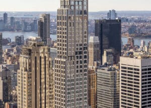 Close-up of 520 Fifth Avenue upper floors showcasing the parametric facade system with arched windows and stepped setbacks against the Manhattan skyline.