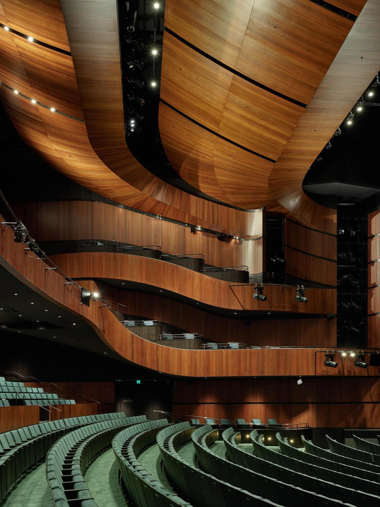 Curved eucalyptus wood balconies and green seating inside the performance hall.