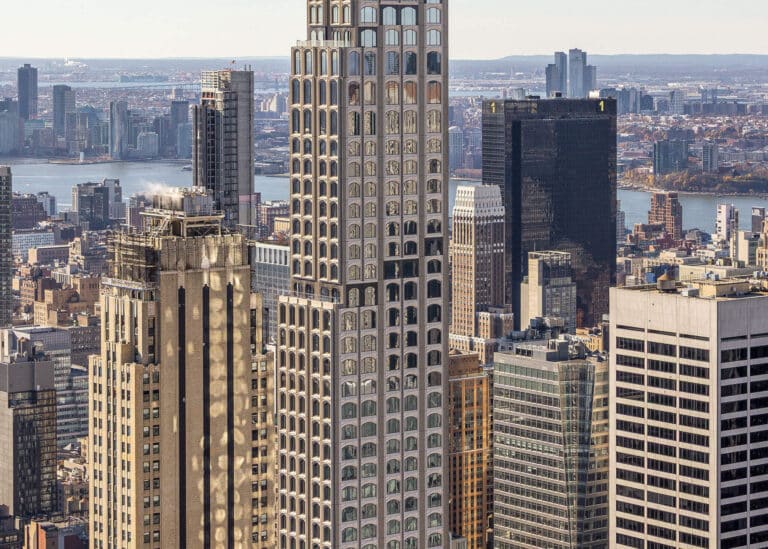 Close-up of 520 Fifth Avenue upper floors showcasing the parametric facade system with arched windows and stepped setbacks against the Manhattan skyline.