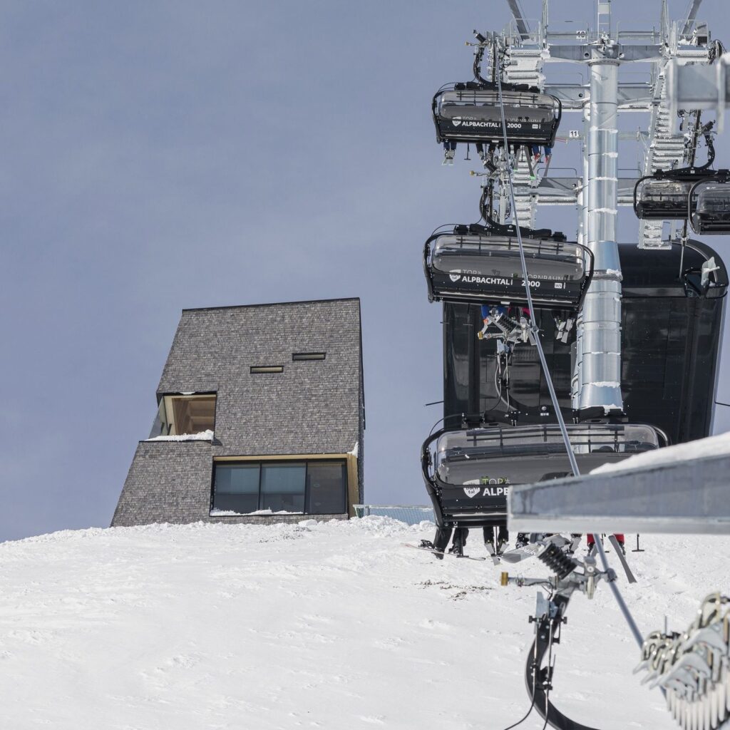 ملجأ جبلي مكسو بالألواح الخشبية يُرى من خلف مصعد كراسي التزلج النشط