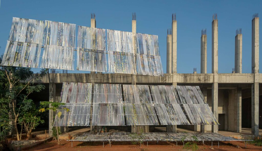 واجهة منشأة معمارية معيارية ليمبو إنغاوا أمام مبنى خرساني غير مكتمل.