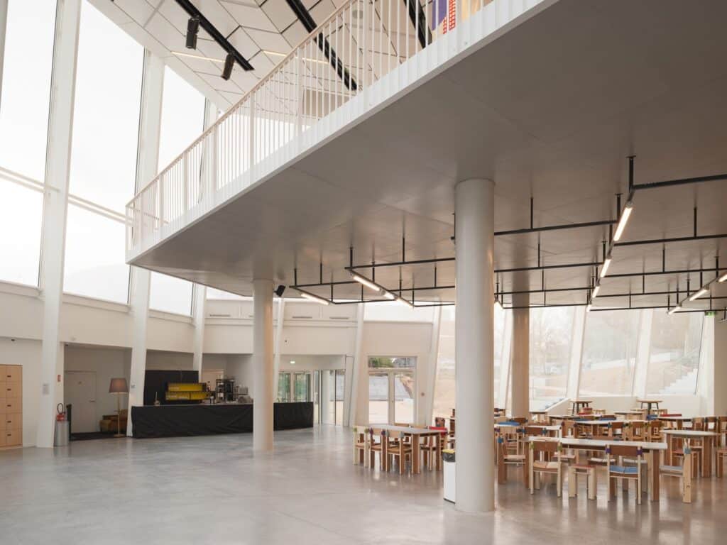 Ground floor cafe and seating area with large structural columns and transparent glass facade.