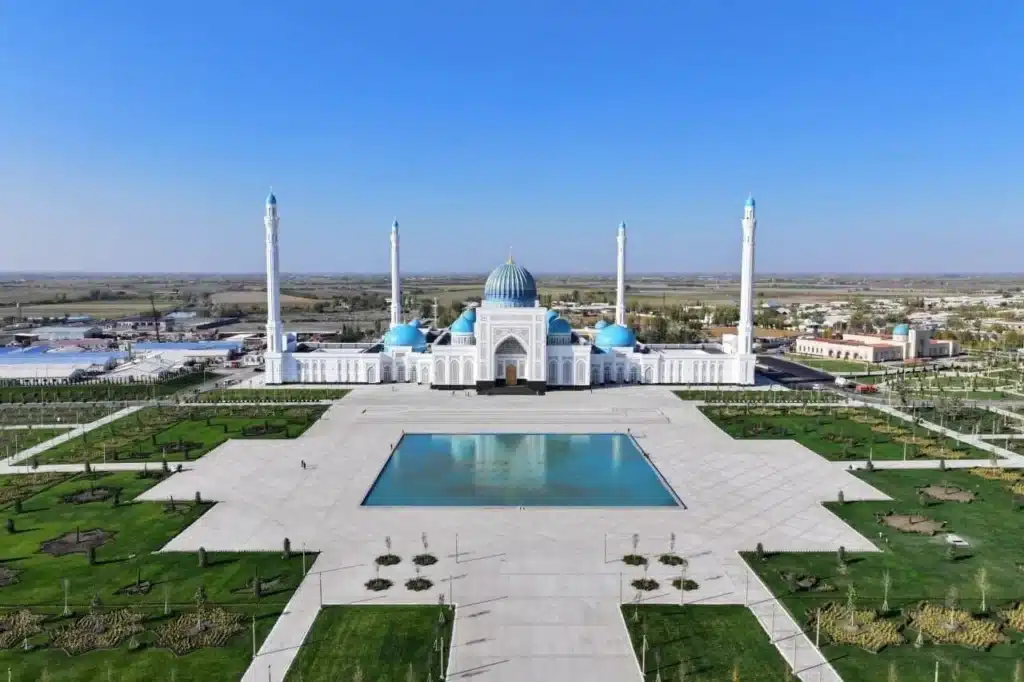 Aerial view of expanded Imam al-Bukhari Complex showing white mosque with blue domes and four minarets