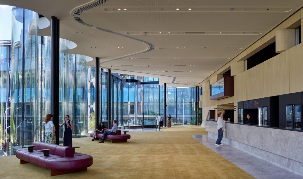 Interior lobby of the Glasshouse Theatre featuring large curved windows and yellow carpeting
