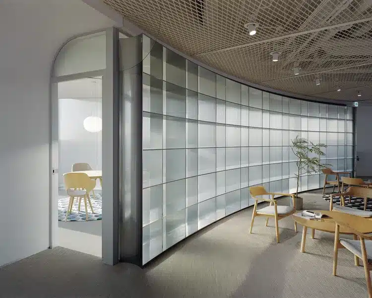 Curved translucent glass wall separating collaborative office spaces
