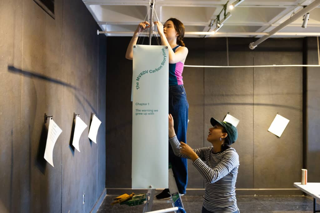 Full gallery view of Carbon Confessions exhibition at Elmaleh Gallery with hanging panels and video projection