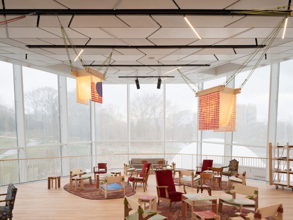 Ground floor cafe and seating area with large structural columns and transparent glass facade.
