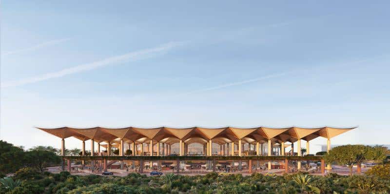 Wide view of the modern Kinshasa Airport terminal building showing its extensive roof structure and surrounding landscape.