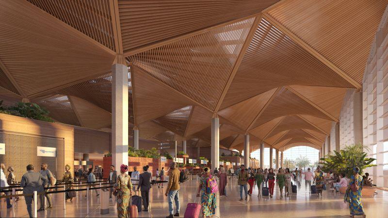 Busy ticketing hall with natural light filtering through slatted wooden ceiling panels and large windows.