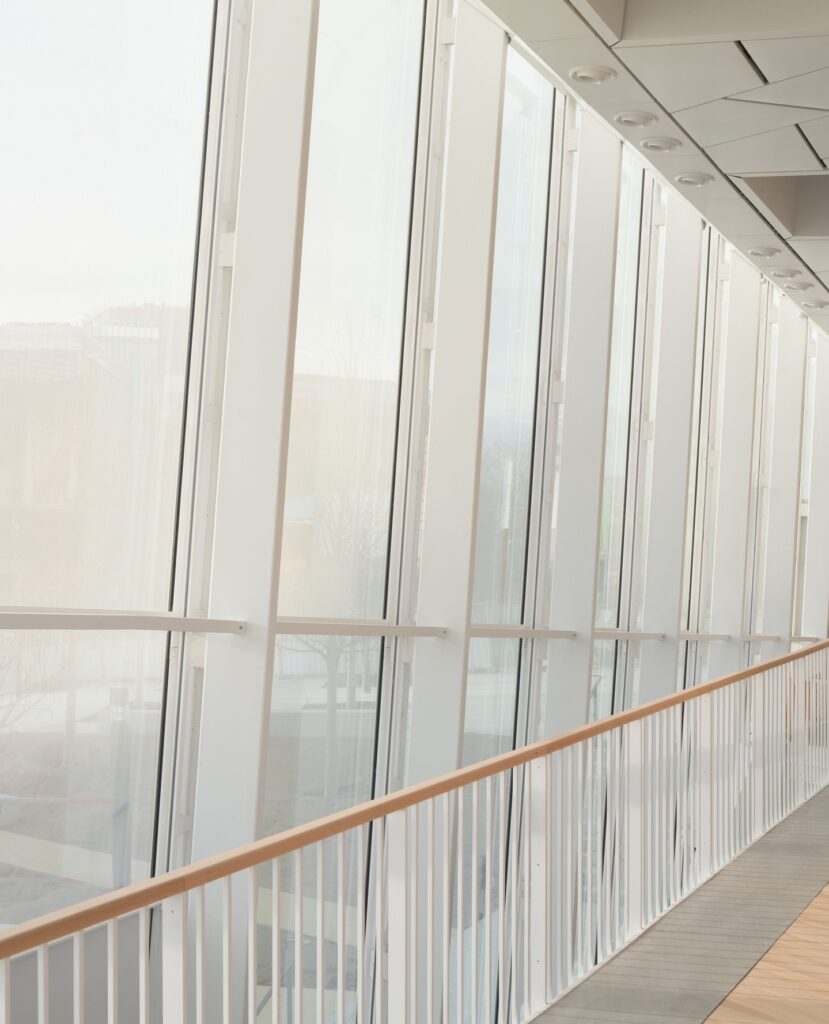 Tall glass facade with white structural mullions viewing the outdoor landscape.