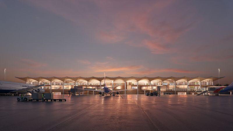 Airplanes parked at the illuminated gates of the Kinshasa Airport terminal during sunset.