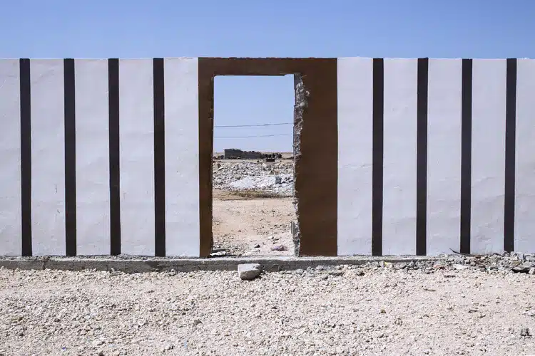 Wall delimiting a construction site in the Western Sahara desert, highlighting human intervention within a vast and contested landscape.