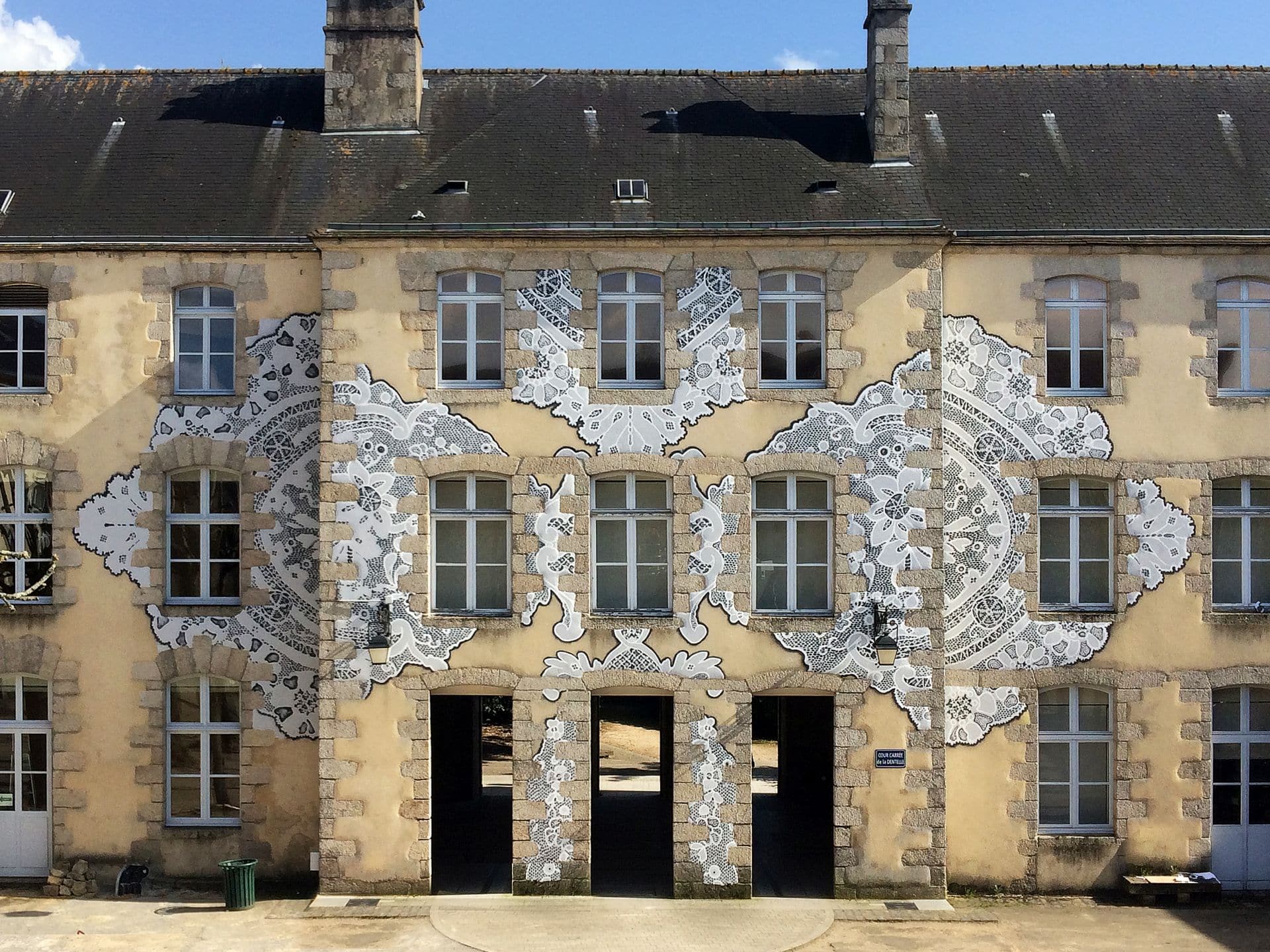 When Lace Becomes Architecture Some artists build a visual language so consistent and so precise that it becomes immediately legible across any surface, any city, any scale. NeSpoon, the Warsaw-based street artist, is one of them. For fifteen years, she has been translating the intricate geometry of traditional Polish lace, specifically the handmade Koniaków patterns originating from the Silesian Beskids, into monumental murals, ceramic installations, and ephemeral street works that now exist across more than 100 cities in 40 countries. Her work has appeared at the Louvre-Lens Museum, the Polish Pavilion at Expo 2020 in Dubai, and the European Parliament. She is currently developing a project connected to the reopening of the Pergamon Museum in Berlin. These are not incidental institutional appearances. They reflect a sustained critical recognition of what NeSpoon is actually doing: rescuing an anonymous, feminine, centuries-old craft tradition from the margins of cultural memory and returning it, enlarged, abstracted, and placed on the most visible surfaces of contemporary urban life. The Mural at DOMOTEKA The new commission is a large-scale mural being created in the main hall of DOMOTEKA Design Centre, Warsaw's first retail destination entirely dedicated to design, located less than twenty minutes from the city centre. Work began in March 2026, with the piece scheduled for completion by the end of the month. Visitors to the venue can observe the process live, from initial sketches through to final detail. The choice of location is worth examining. DOMOTEKA is not a gallery or a museum. It is a commercial design centre housing over 600 brands. The decision to invite NeSpoon to create a permanent mural in its primary circulation space is a statement about the relationship between retail, design, and public art, and about what kind of experience a design-focused commercial venue can credibly offer beyond the transactional. Agata Brzezińska, Senior Director and Head of CEE at Pradera, the fund that owns DOMOTEKA, framed the invitation as a natural continuation of the venue's identity: a place oriented toward quality, design, and interior architecture that aims to be more than a commercial space. Art here is not decoration. It is meant to generate a different kind of engagement with the space. The Source Material: Koniaków Lace Understanding the mural requires understanding the source. Koniaków lace is a craft tradition associated with the village of Koniaków in southern Poland, produced almost exclusively by women using needles and thread, with patterns passed between generations without written documentation. The designs are characterised by radial symmetry, dense interlocking curves, and a structural logic that is at once highly decorative and geometrically rigorous. NeSpoon's relationship to this material is neither nostalgic nor ethnographic. What she extracts from it is the structural principle, the underlying geometry of intersection, repetition, and void, and she scales it to the dimensions of a building facade or, in this case, a commercial hall. The anonymity of the original makers is part of what she is addressing. These patterns were created by women whose names were never recorded. Placing them on the surfaces of cities is one way of insisting on their presence in cultural memory. Scale, Surface, and the Logic of the Work At a monumental scale, lace undergoes a transformation that is not merely quantitative. What reads at close range as textile, intimate, tactile, domestic, becomes at building scale something closer to structural drawing. The voids that define the pattern in fabric become negative space in a mural composition. The threads become lines. The result has been described accurately as resembling delicate openwork structures floating across facades, which is the visual quality that has made NeSpoon's murals globally circulated images: they are simultaneously recognisable as pattern and as architecture. The interior environment of DOMOTEKA presents different conditions than the exterior facade. Controlled light, a defined ceiling height, a nd a surrounding context of furniture showrooms and design objects. Interior murals of this scale carry a different relationship to the viewer: the distance is fixed, the approach is frontal, and the context is commercial rather than civic. These are not deficiencies. They are simply different spatial terms that the work must negotiate. ✦ ArchUp Editorial Insight The DOMOTEKA commission raises a question increasingly relevant in contemporary design culture: what does it mean for a commercial retail venue to commission serious public art? NeSpoon's source material, anonymous, feminine, pre-industrial craft, carries enough cultural specificity that it cannot be reduced to decorative wallpaper without remainder. The Koniaków tradition is not a generic pattern. It is geographically specific, socially embedded knowledge production that happens to generate extraordinary visual material. Whether the interior commercial context sustains that specificity, or flattens the work into atmosphere, will depend partly on how the venue contextualises the commission and partly on the intrinsic qualities of the work itself, which across very different urban environments have consistently proven durable. Conclusion The DOMOTEKA mural is a genuine test of what public art can do inside the spaces of everyday commercial life. It is worth following not as a marketing exercise but as a case study in how craft memory, street art practice, and the designed interior can meet, and what each gives up or gains in that encounter.