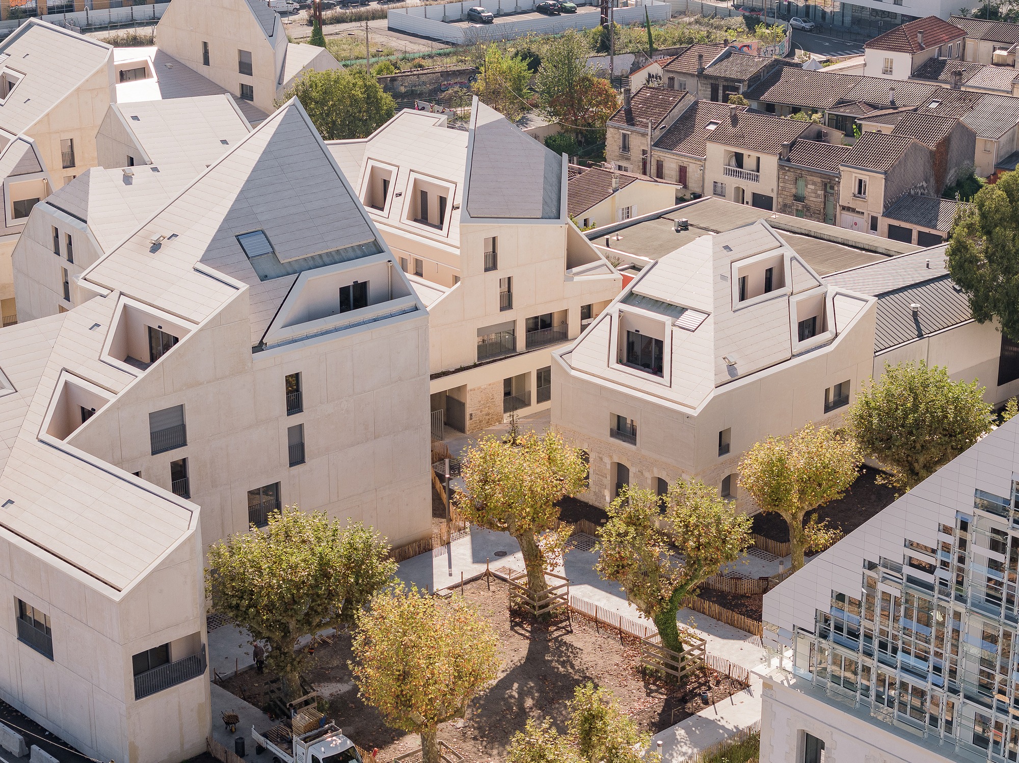 Aerial drone view of Bastide-Niel housing project showing fragmented rooflines and urban integration in Bordeaux.