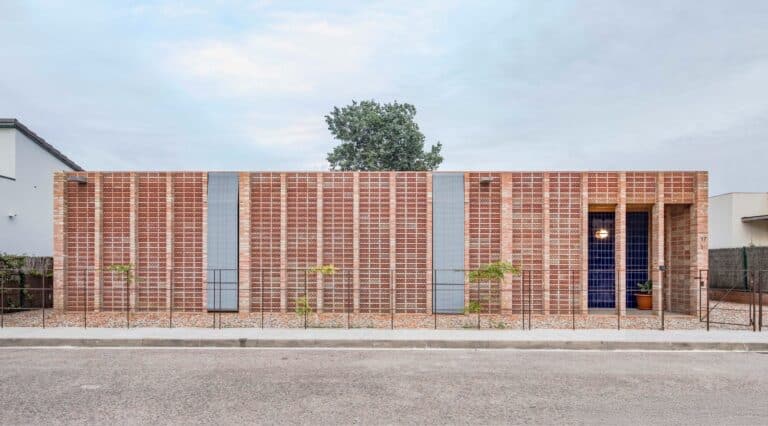 Exterior view of House 1603 by HARQUITECTES showing a solid brick facade and ceramic perforated screens in Sant Esteve de Palautordera.