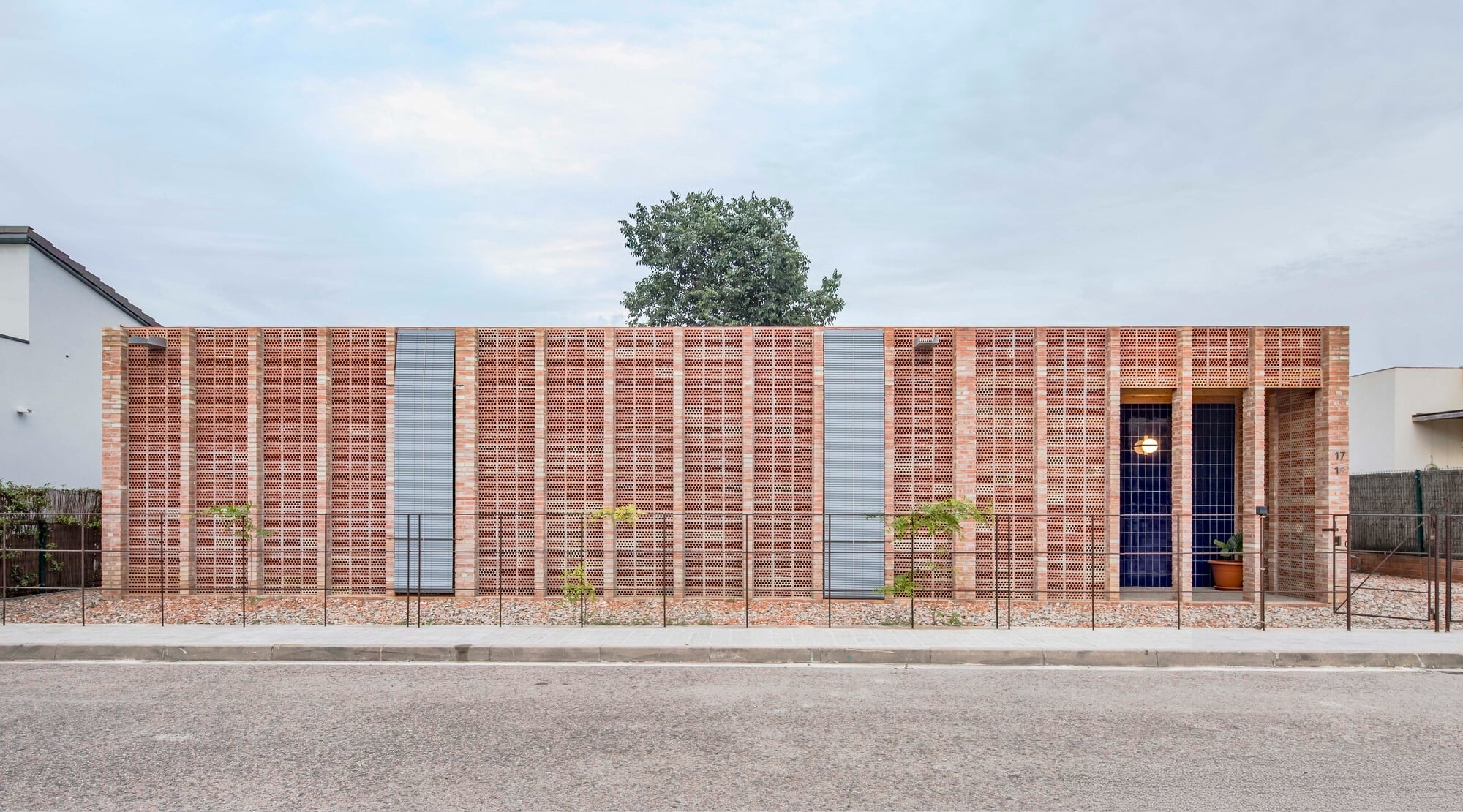 Exterior view of House 1603 by HARQUITECTES showing a solid brick facade and ceramic perforated screens in Sant Esteve de Palautordera.