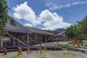 Children playing in the outdoor amphitheater and courtyard of Sonomoro School in Peru, featuring wooden structures and a central orange grove.