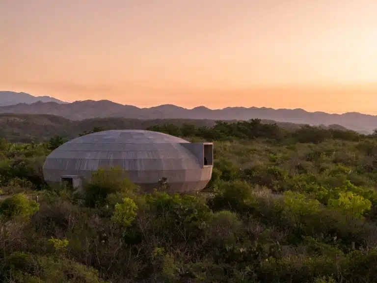 Exterior view of the cylindrical concrete Mushroom Pavilion at Casa Wabi during sunset, surrounded by dense Oaxacan vegetation.