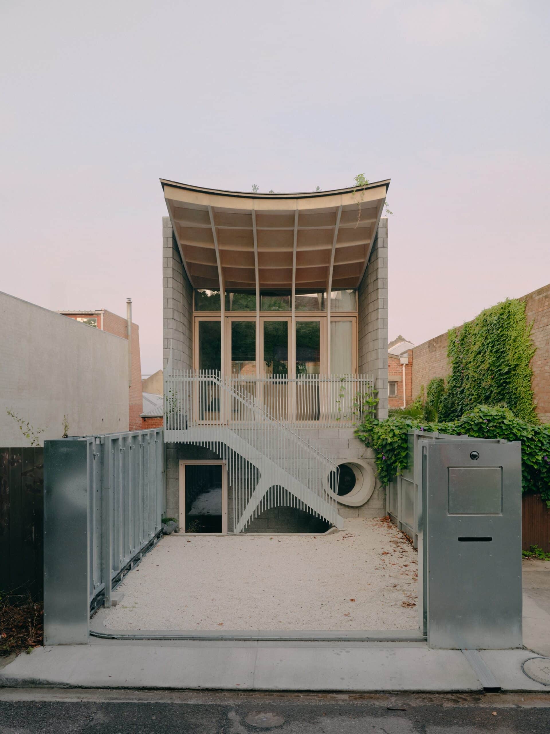 Front facade of Northcote House in Melbourne featuring a timber curved roof, concrete block walls, and an Engawa-inspired entrance terrace.