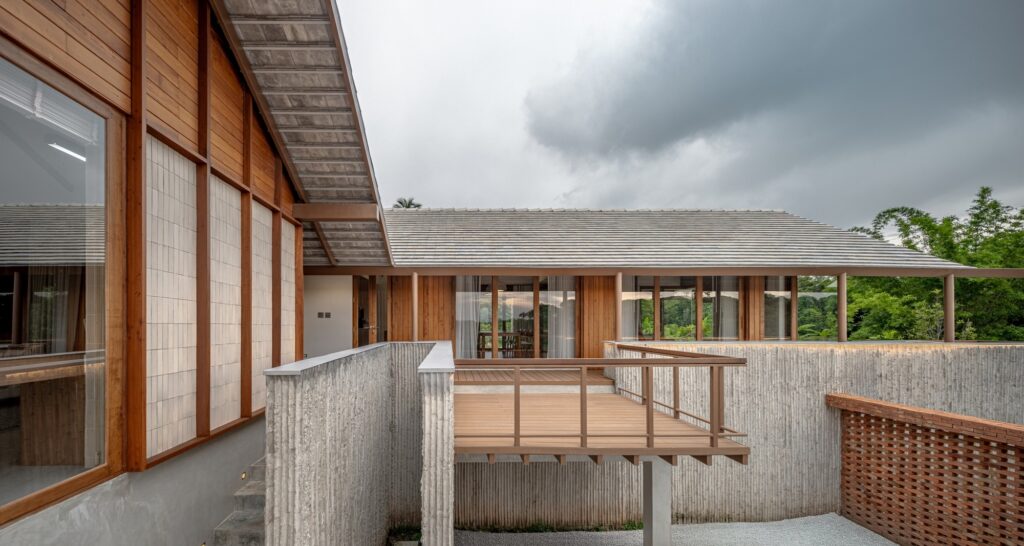 Architectural detail of a cantilevered wooden deck (Tern) and textured concrete walls with bamboo patterns.