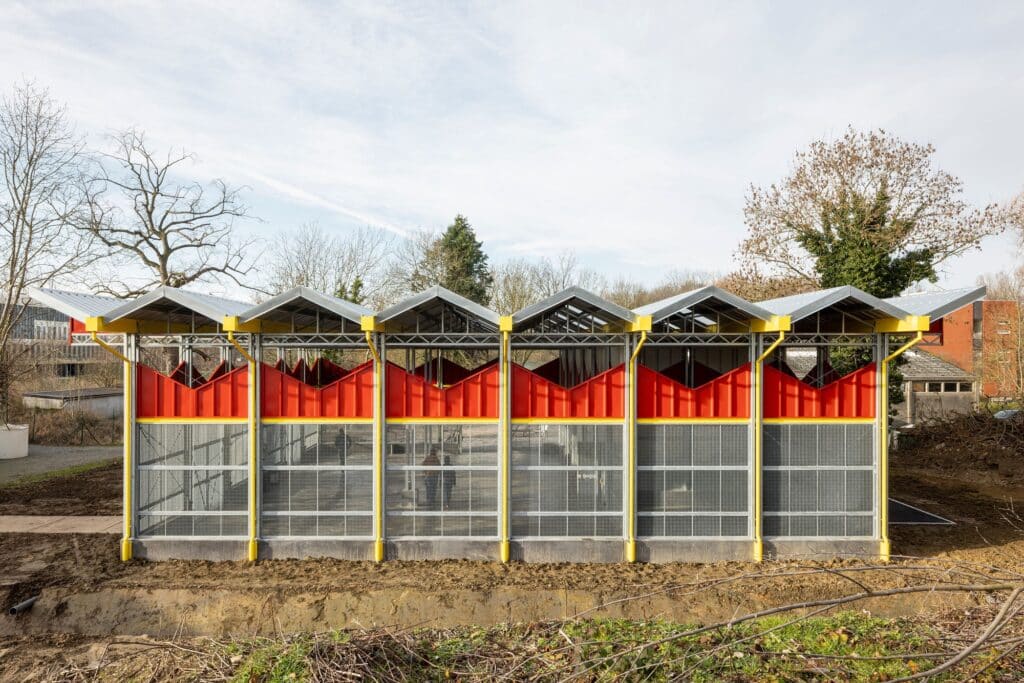 Side view of the aquatic research facility at the University of Antwerp, featuring metal mesh screens and a sawtooth roof design.
