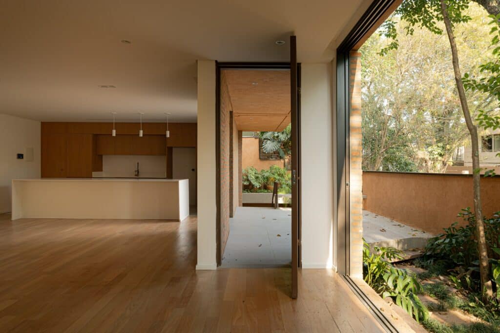 Open plan interior showing a modern kitchen with wooden cabinets and a large sliding door opening to a garden.