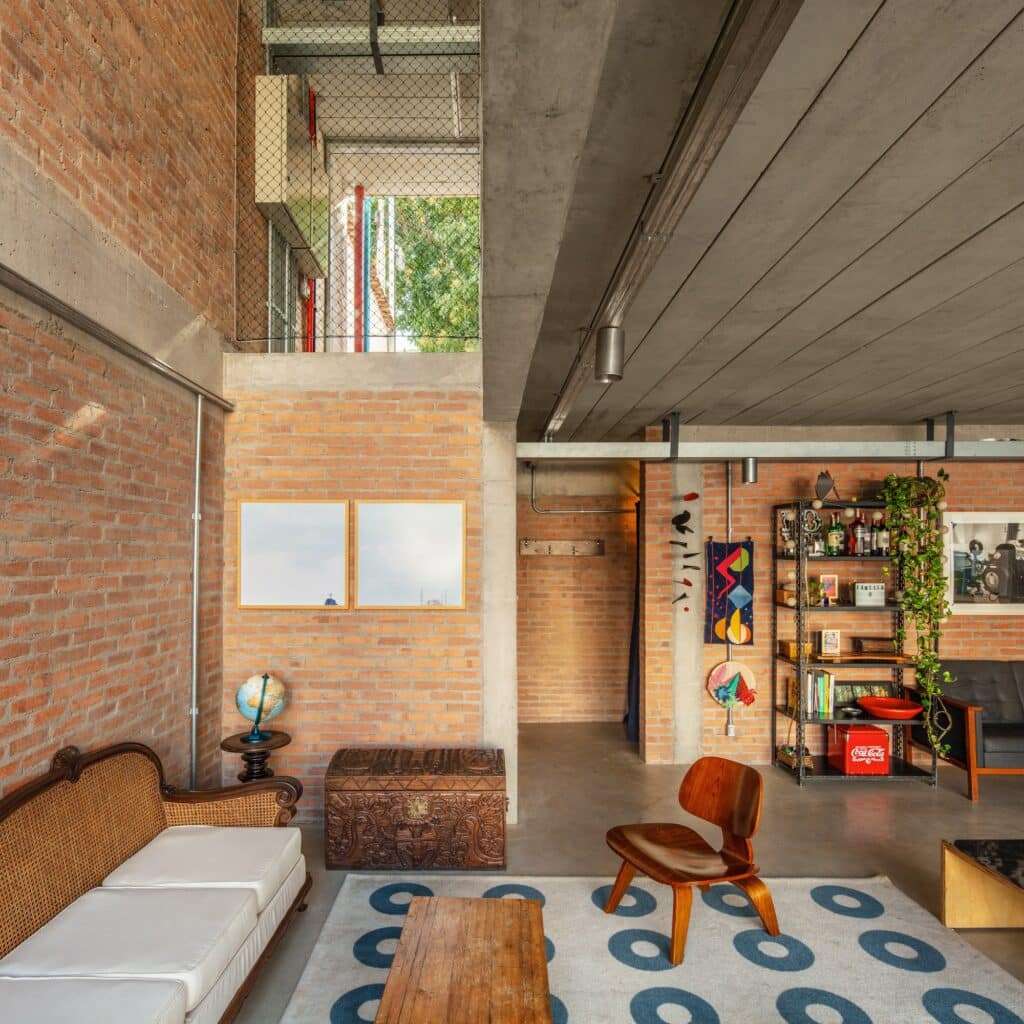 Interior living room of Caet&eacute;s House with exposed brick walls, concrete ceiling, and mid-century modern furniture.
