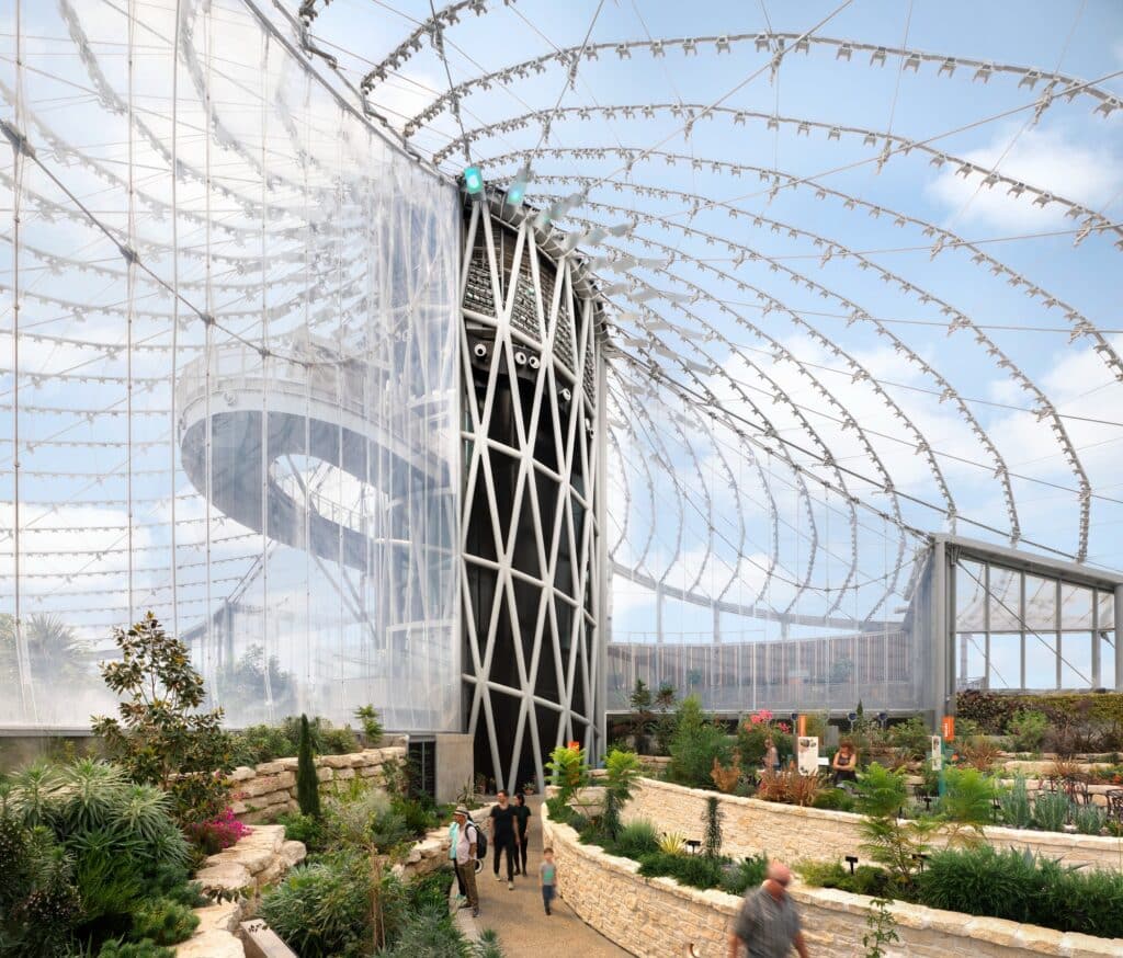 Interior view of the biome at The Leaf showing the complex steel cable net structure supporting the translucent ETFE roof and a central spiral core.