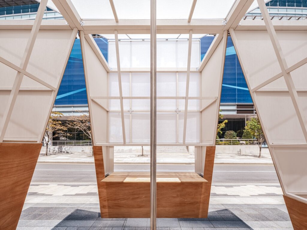 Symmetrical interior shot of the TEUM pavilion featuring a central bench and framed views of the street outside.