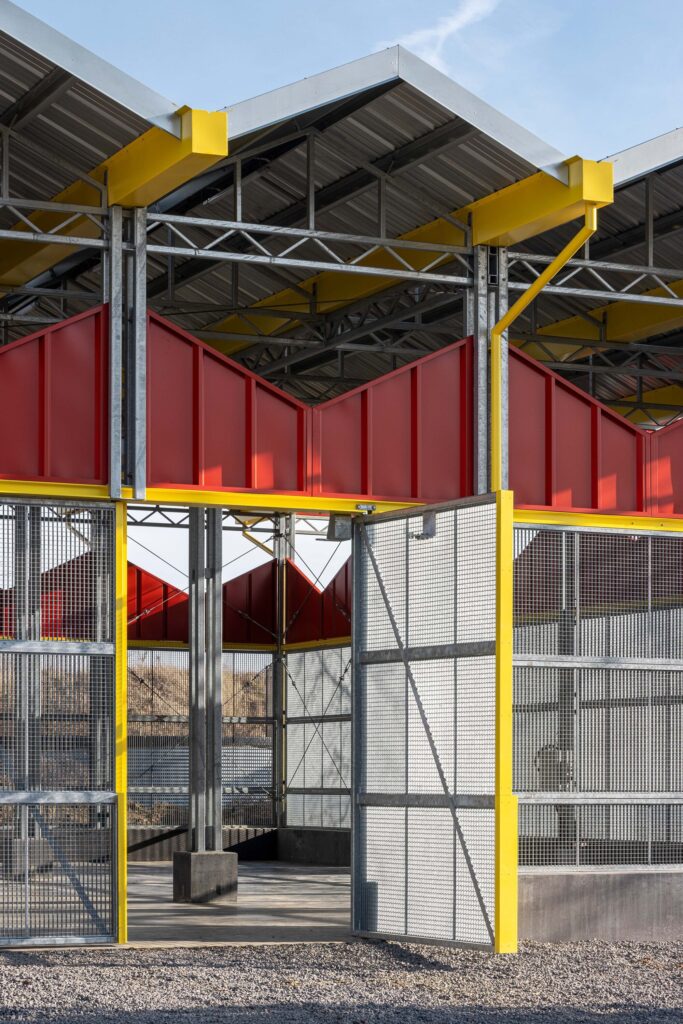 Close-up of the large 4m x 3.3m sliding mesh gates and yellow structural details of the research barn.
